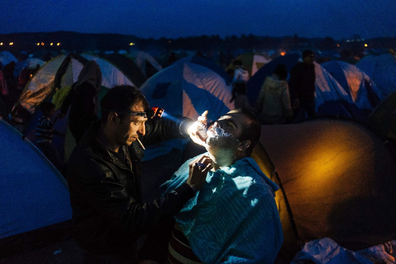 Un barbero sirio afeita la barba de un cliente en un campamento de inmigrantes cerca de la frontera entre Grecia y Macedonia.