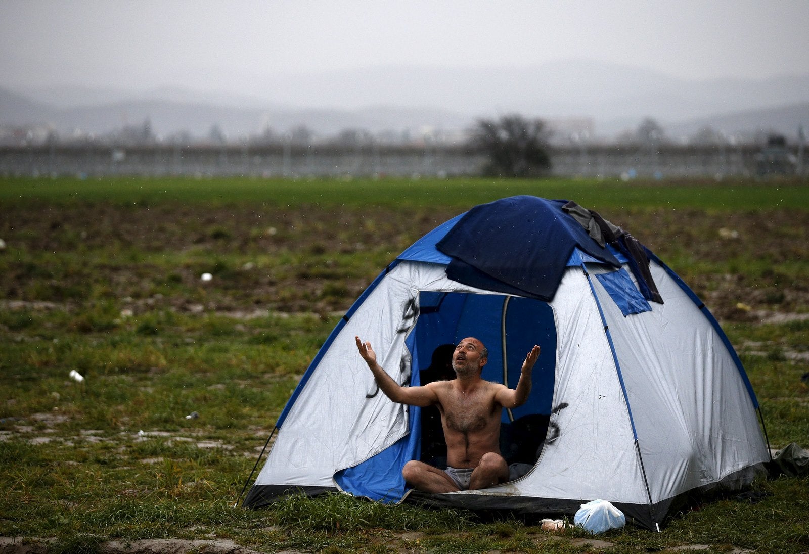 Un inmigrante, que está esperando para cruzar la frontera entre Grecia y Macedonia, reacciona al ser fotografiado en un campamento provisional cerca del pueblo de Idomeni, Grecia