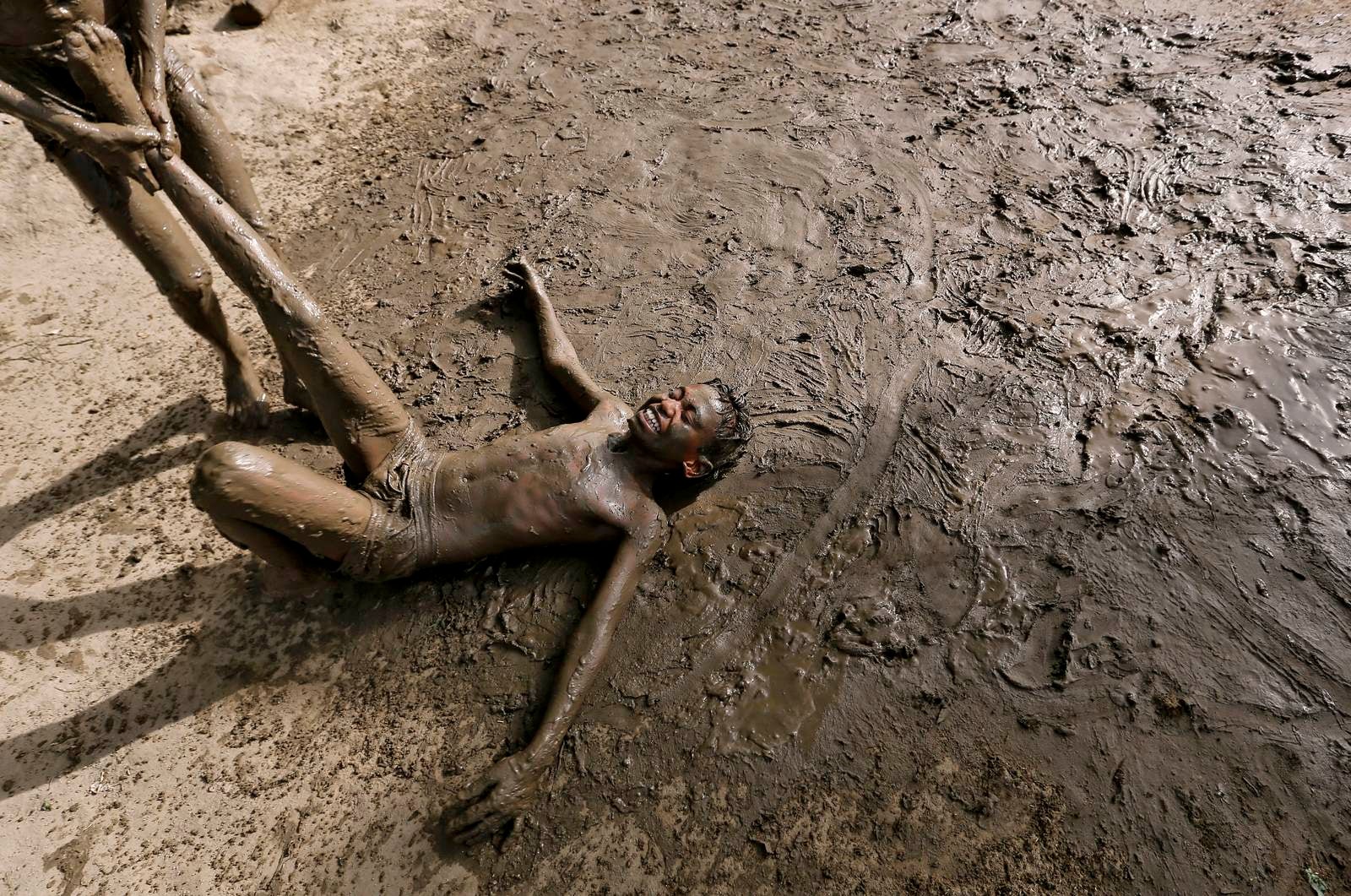 Los niños juegan en el barro para refrescarse en un día caluroso en Nueva Delhi, India