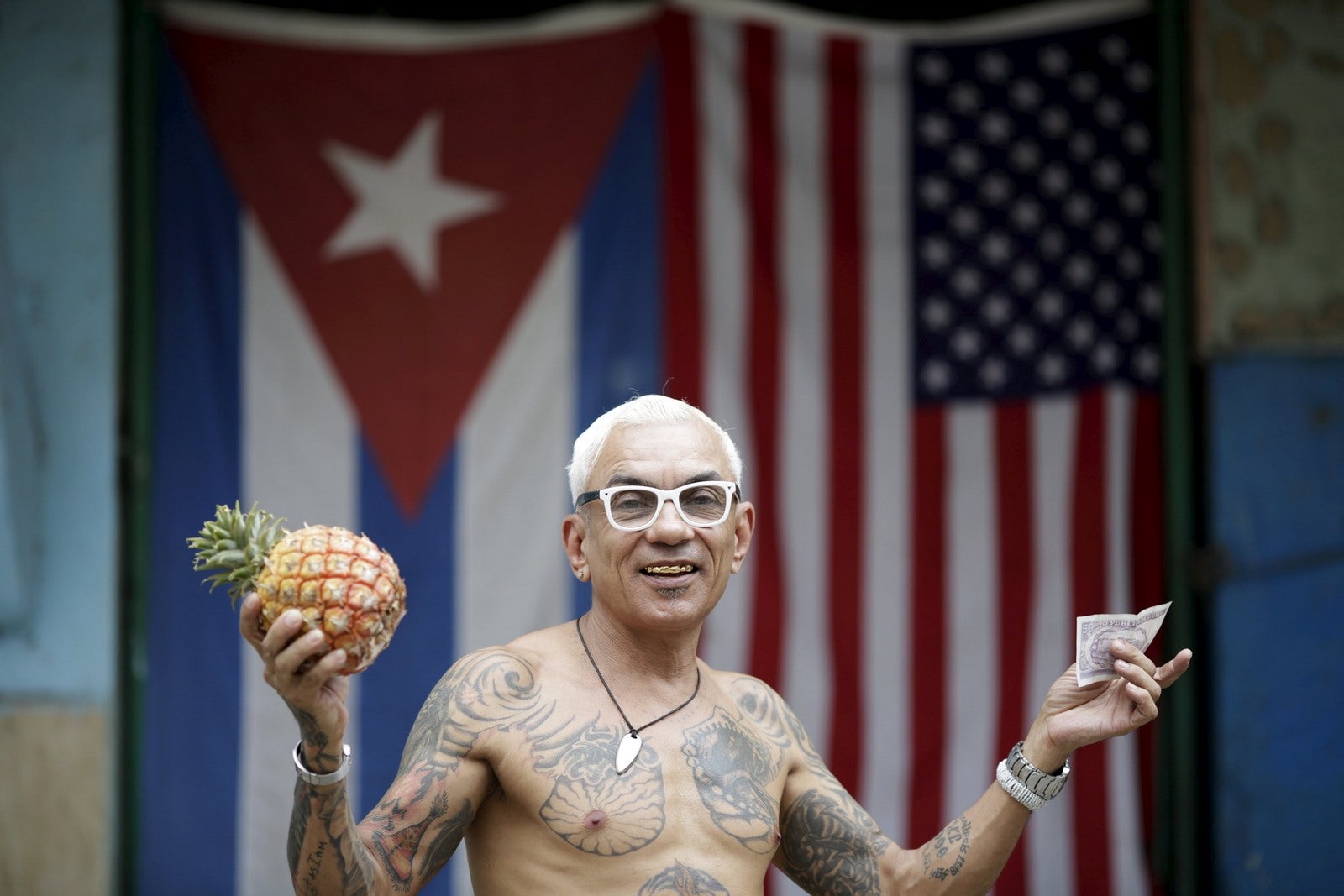 Zamora, de 55 años, posa para una fotografía delante de las banderas de Cuba y Estados Unidos después de comprar una piña en La Habana