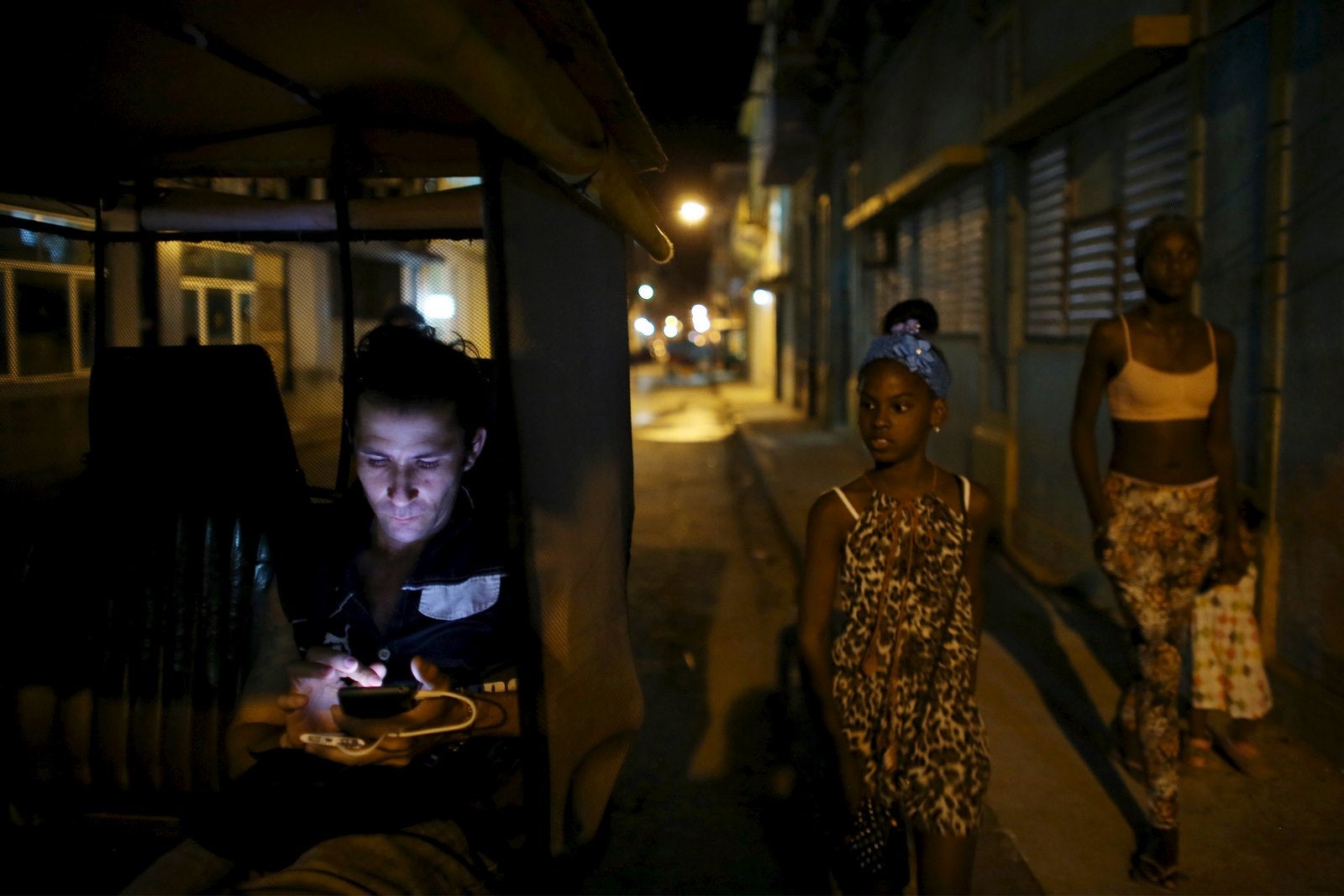 El conductor de bicitaxi Danilo Guerra, de 25 años, usa su teléfono móvil mientras espera a los clientes en el centro de La Habana