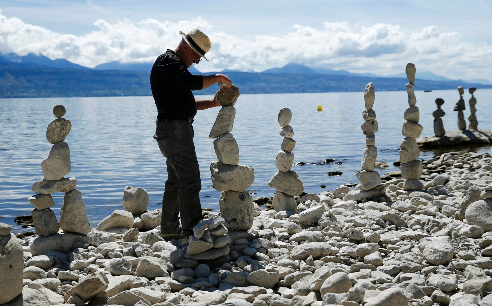 El artista Daniel Dunkel construye un montículo de piedras en la costa del lago Leman en Lutry, cerca de Lausana.