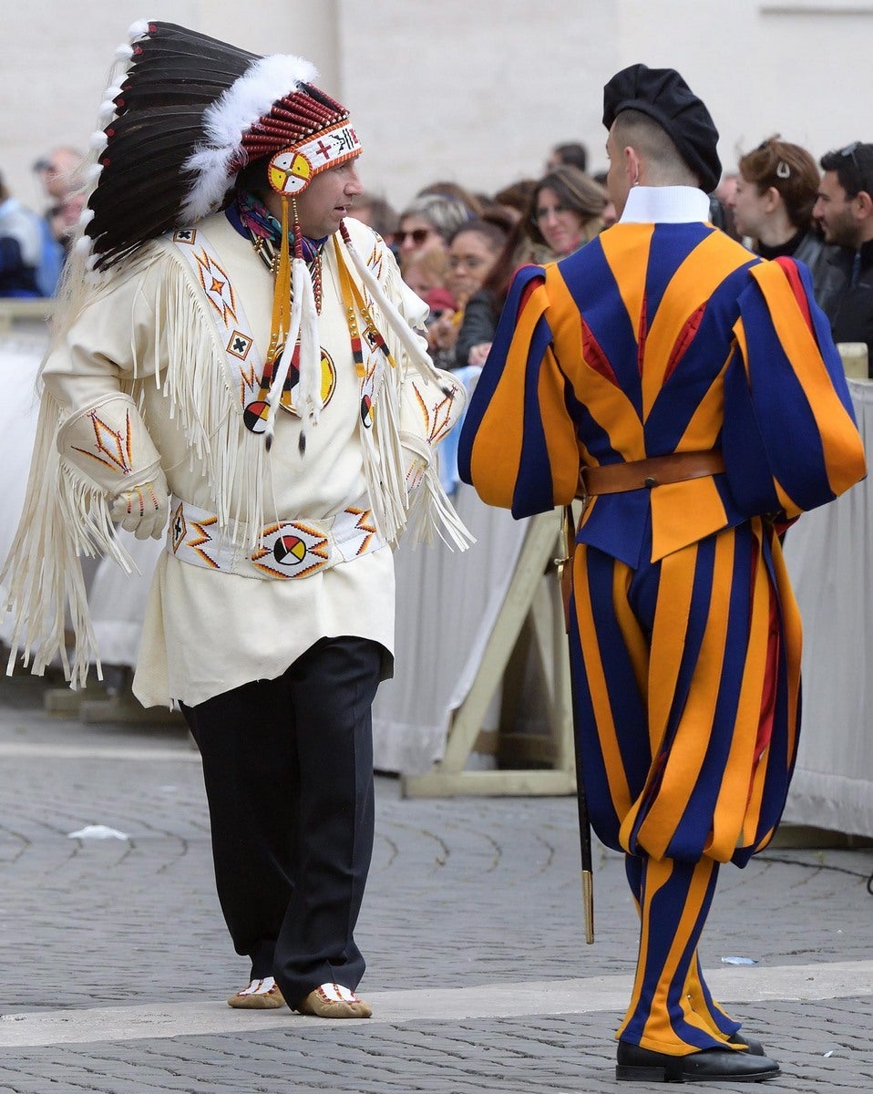 Un miembro de la Guardia Suiza se gira para contemplar a un indio nativo americano durante la audiencia general que celebró el papa Francisco en la Plaza de San Pedro del Vaticano.