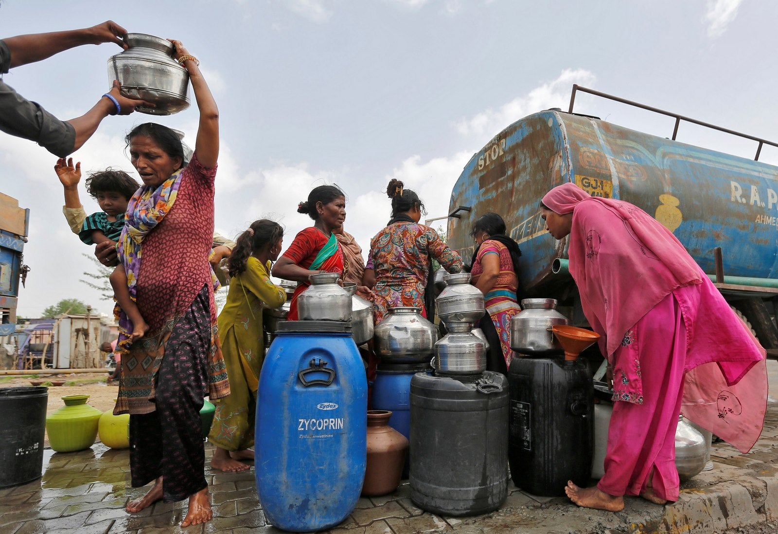 Habitantes de Ahmedabad llenan recipientes vacíos con agua de un camión cisterna un día caluroso de verano.