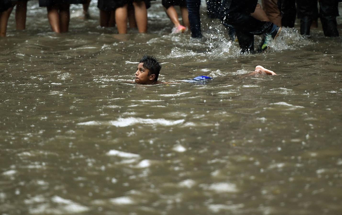 Un joven indio juega en las aguas de una calle inundada durante las lluvias fuertes en Bombay.