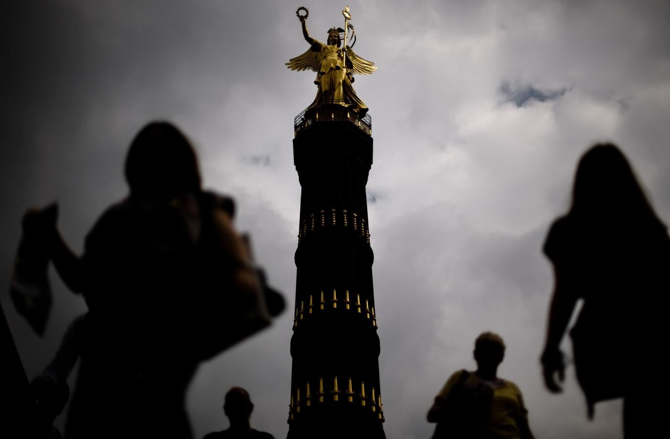 La gente pasa por la escultura de bronce de La Victoria en Berlín.