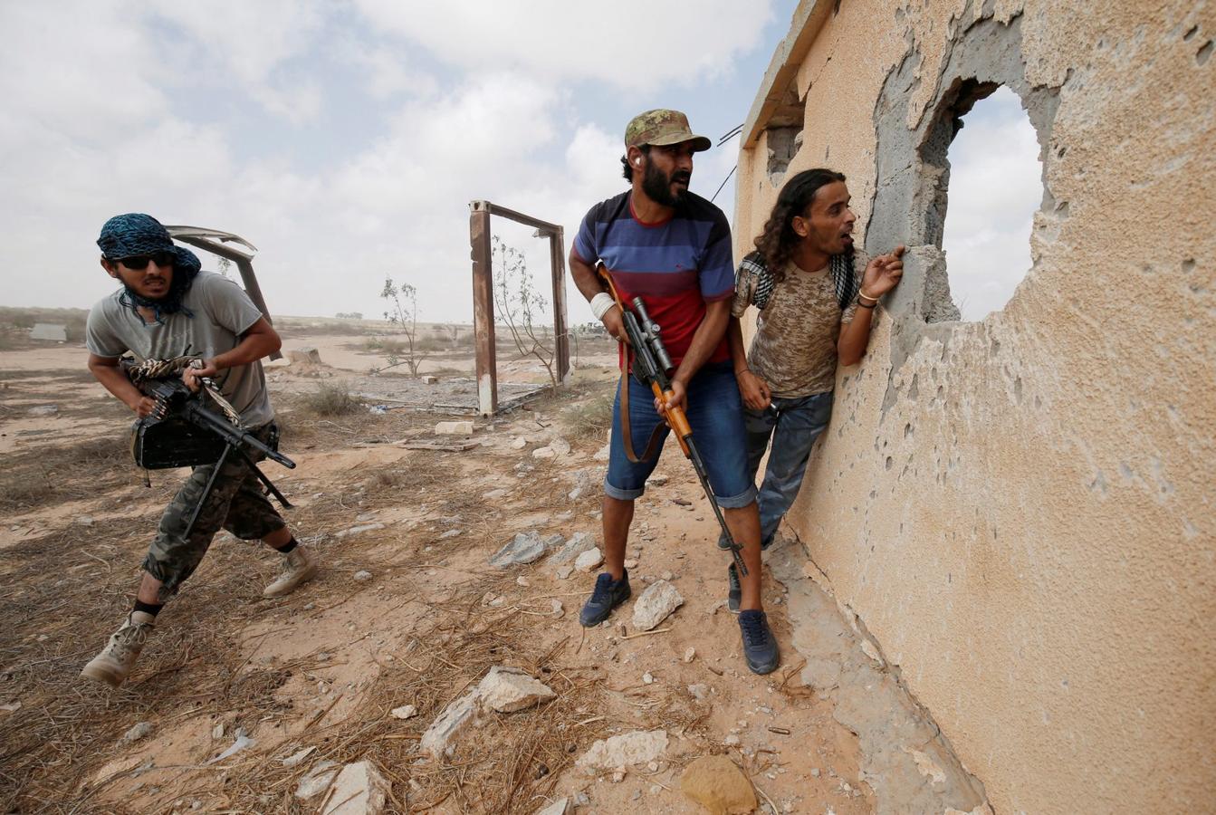 Las fuerzas libias aliadas con el gobierno respaldado por U.N. a cubierto durante una batalla con los combatientes estado islámico en Sirte.