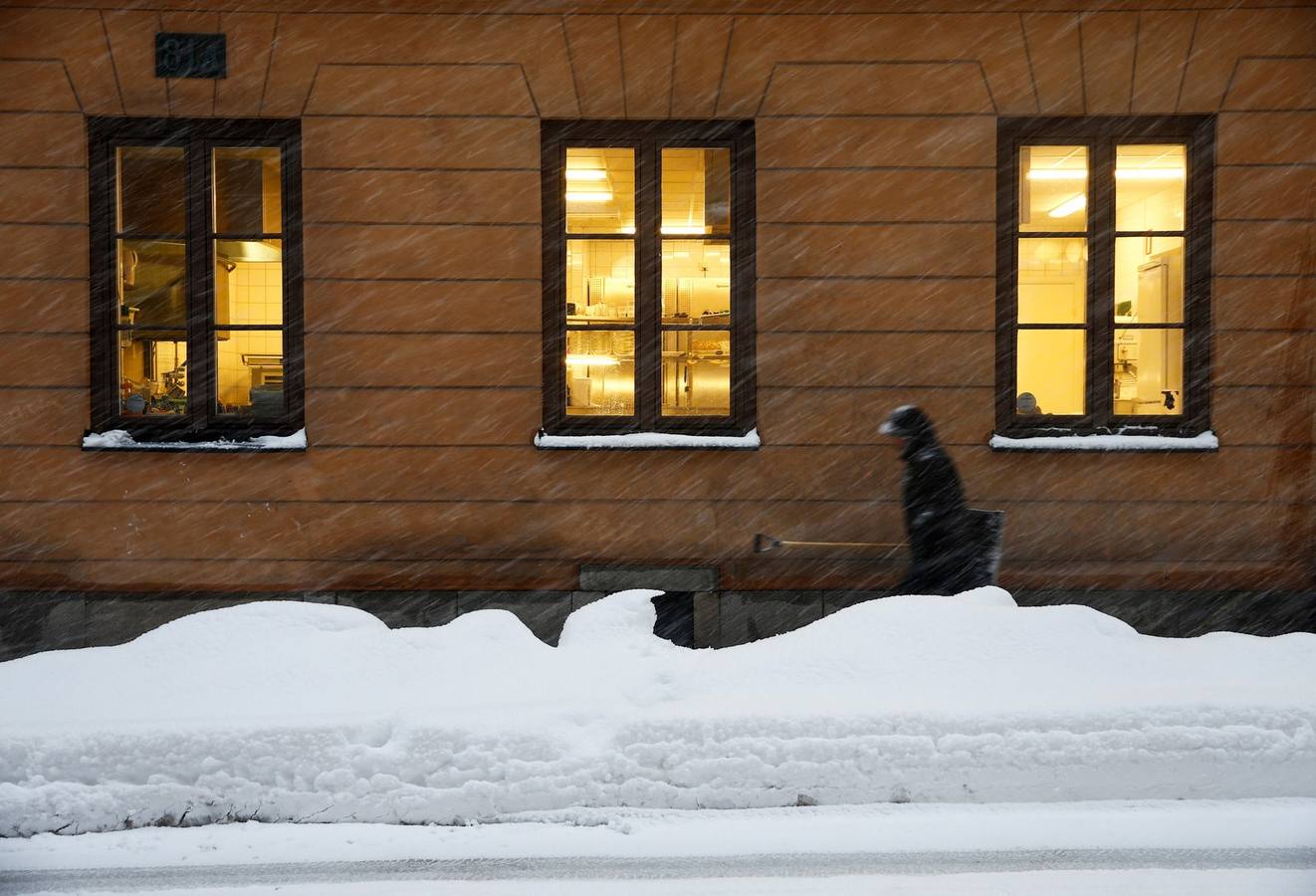 Un hombre con una pala camina por la calle durante una fuerte nevada en Estocolmo.