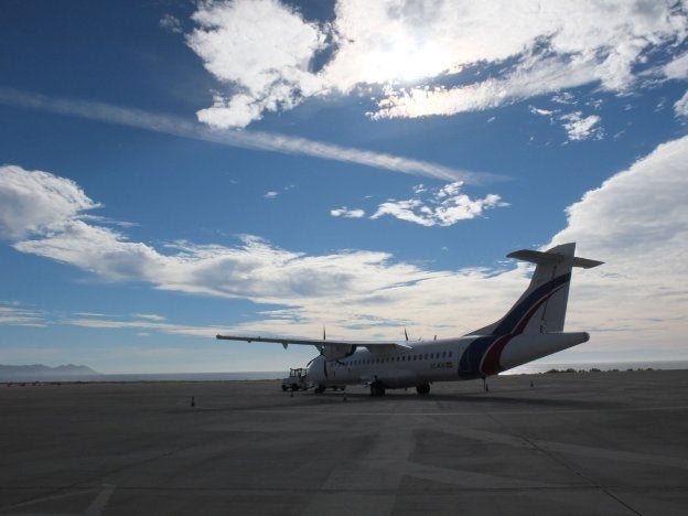 Una aeronave, estacionada en la plataforma del Aeropuerto de El Alquián con el Cabo de Gata y la bahía de Almería al fondo.
