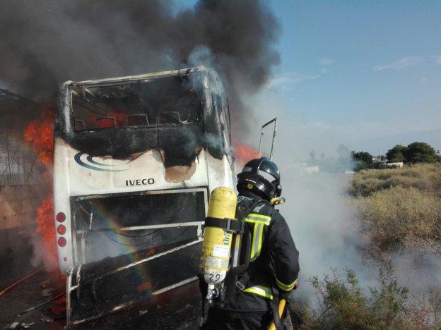 Un bombero hace frente a las llamas que rodean al microbús.
