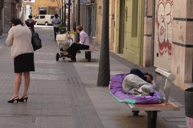 Un hombre duerme en un banco en una céntrica calle de Almería capital.