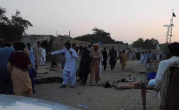 Varias personas, junto a los cuerpos de las víctimas del atentado.