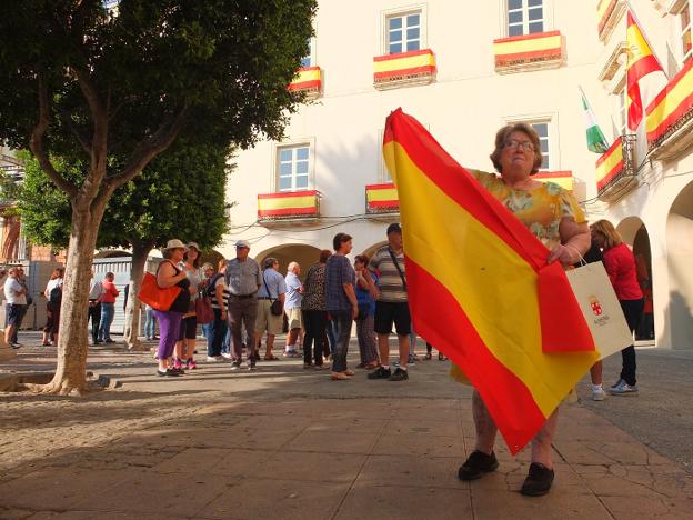 Una mujer muestra la bandera recogida en una Plaza Vieja llena de gente.