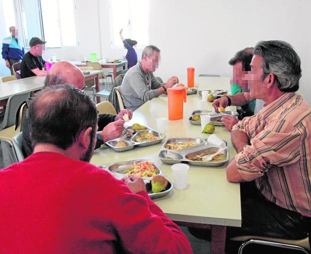 Varios usuarios comen en la zona de comedor del centro municipal de acogida de Almería.