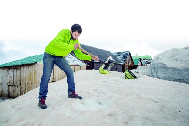 Israel Fernández retira nieve de la puerta de su establecimiento, donde alquila trineos para las familias en la Hoya de la Mora.