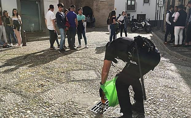 Un policía vacía una bolsa con bebidas alcohólicas en el Día de la Cruz.