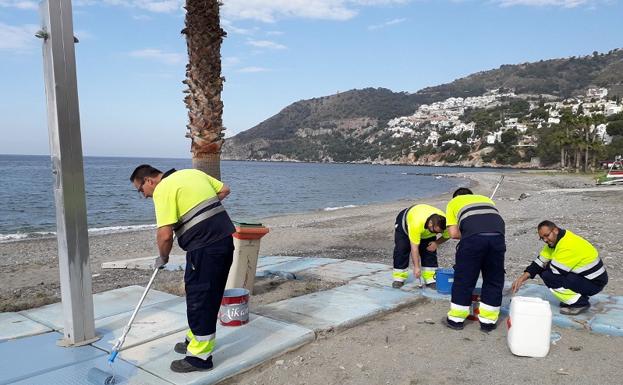 Operarios pintando pasarelas en la playa de La Herradura. 