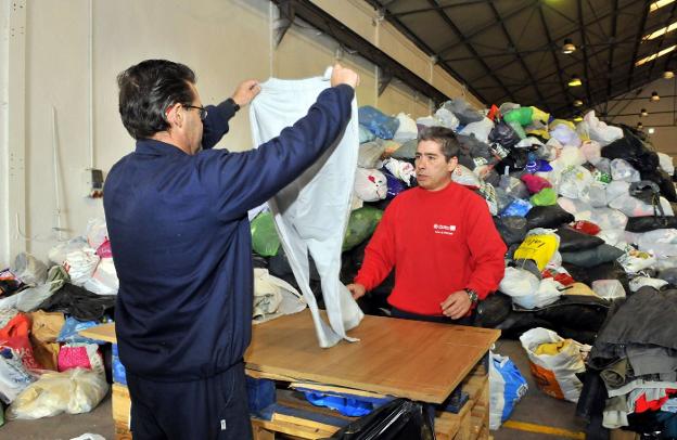 Empleados de Cáritas Diocesana en Linares trabajan en la nave cedida por el Ayuntamiento de Linares para reciclar ropa para personas necesitadas. 