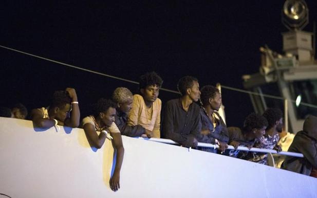 Varios migrantes esperan antes de desembarcar de la nave de Frontex.