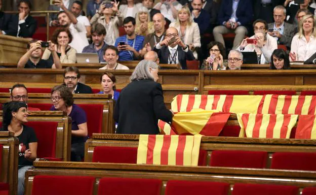 Una diputada retira las banderas de España de los escaños vacíos del PP durante la votación de la ley del referéndum.. 