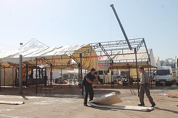 Dos caseteros recogiendo ayer la lona de una de las casetas del recinto ferial. 