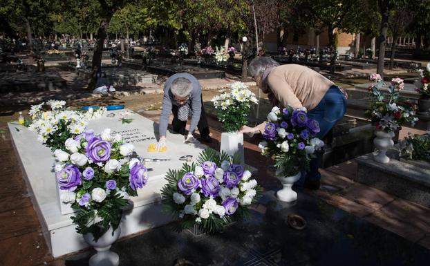 Dos mujeres limpian una tumba en el cementerio municipal de San José.
