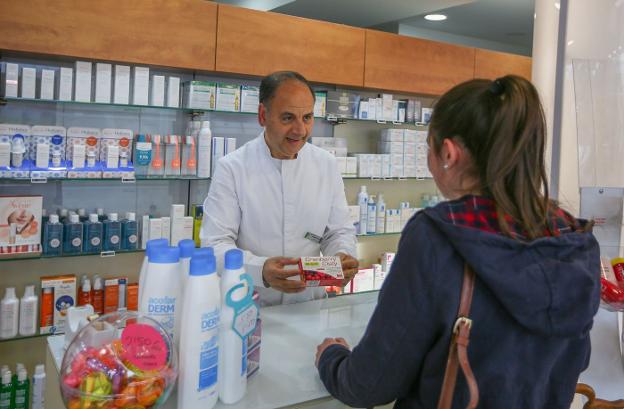 Una farmacéutico dispensa un medicamento a una cliente.