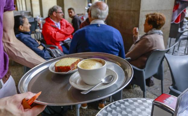 Un camarero lleva un servicio a varios clientes en un bar del centro de Vitoria. 