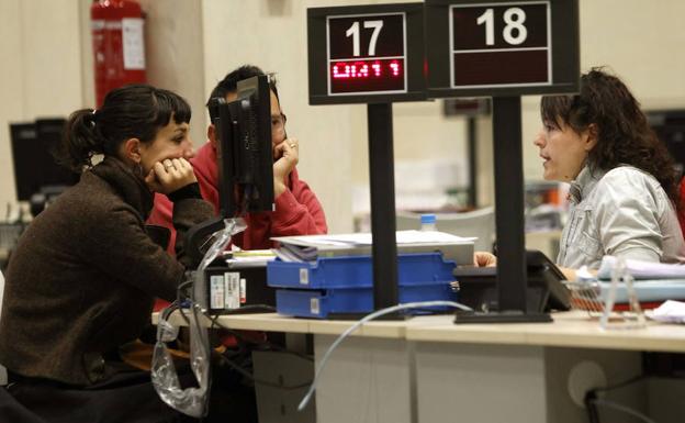 Una funcionaria atiende a dos jóvenes desempleados en los servicios públicos de empleo.