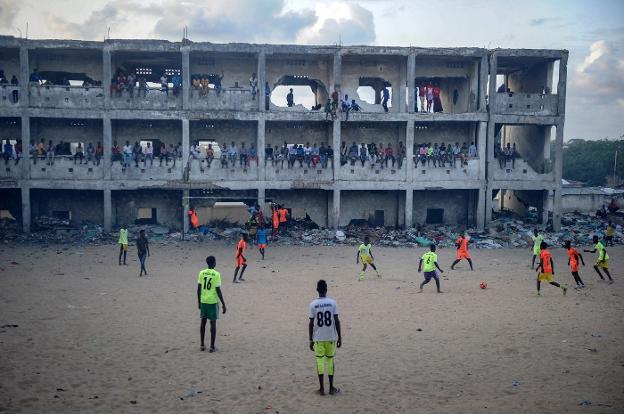 Partido de fútbol en el patio de un colegio de secundaria destrozado por las bombas. 