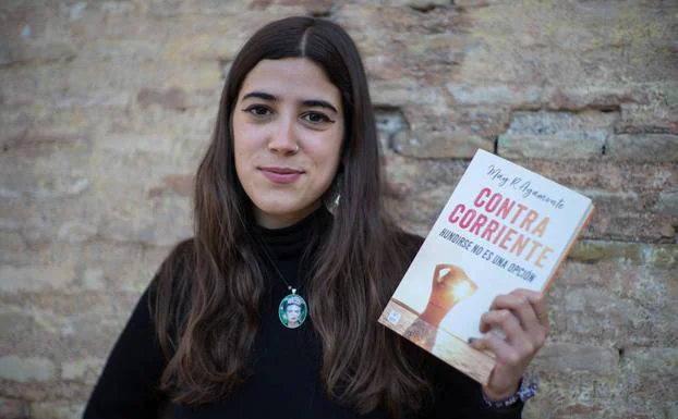 May R. Ayamonte posa con su libro 'Contracorriente' frente al Arco de Elvira en Granada.
