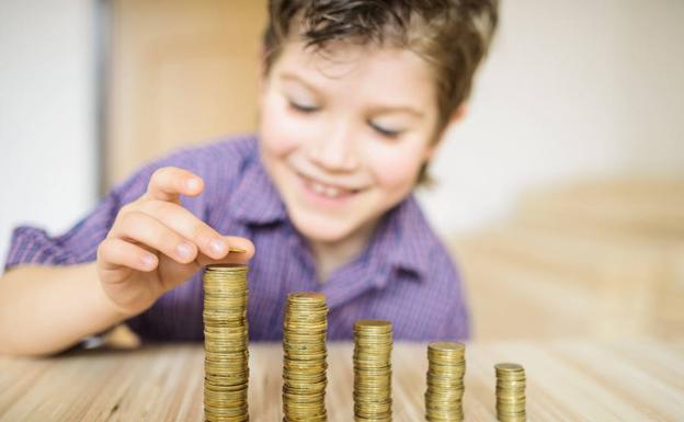 Un niño cuenta montoncitos de monedas.