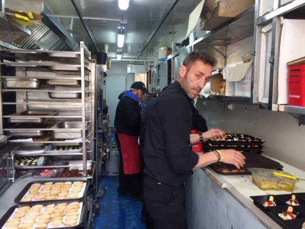 Los cocineros se afanan en la preparación de las comidas en el interior del camión.