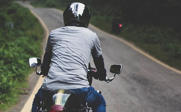 Un joven circula en moto por una carretera.