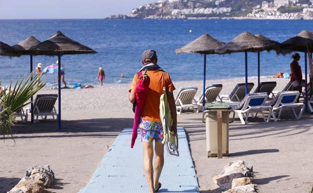 Un turista se dirige a la orilla de la playa San Cristóbal de Almuñécar para disfrutar de sol y del mar.