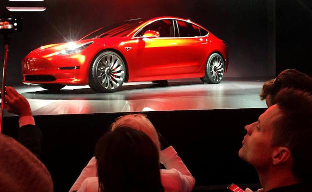 Varias personas ven un modelo de Tesla. 