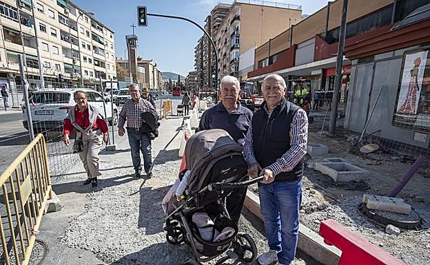 Sebastián y 'Rufo', que lleva a su nieta en el carrito, en medio de las obras de rediseño de la carretera antigua de Málaga.