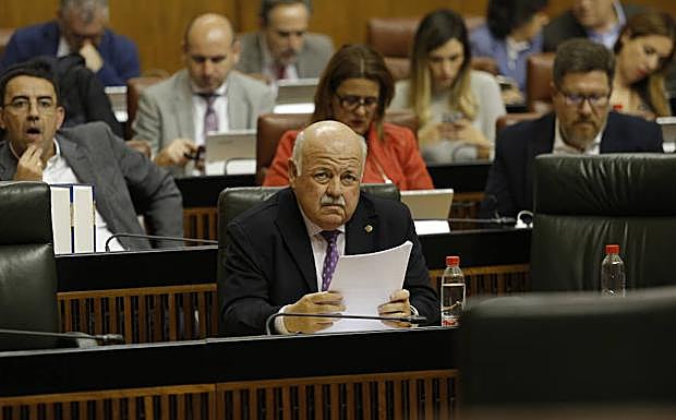 El consejero de Salud, Jesús Aguirre, sentado en su escaño delante de la bancada socialista, con su portavoz, Mario Jiménez, detrás.