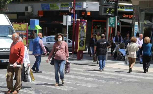 Una mujer con una mascarilla cruza por un paso de peatones en una imagen de archivo.