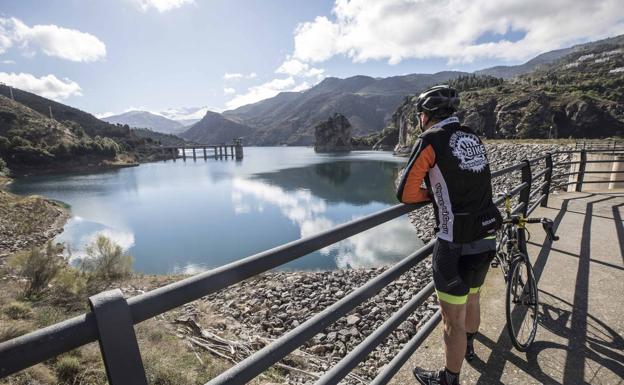 Un aficionado a la bicicleta observa el pantano de Canales en el ascenso por la carretera de Güéjar Sierra.