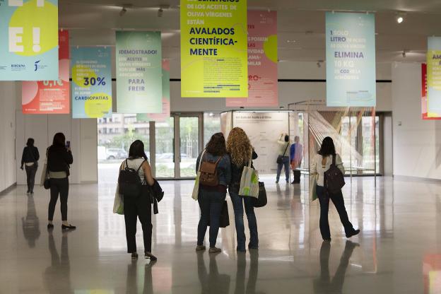 Jóvenes observan un cartel del Congreso O_live en Jaén.