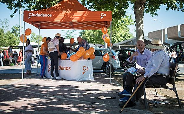Tres ancianos conversan junto al tenderete de Cs. 