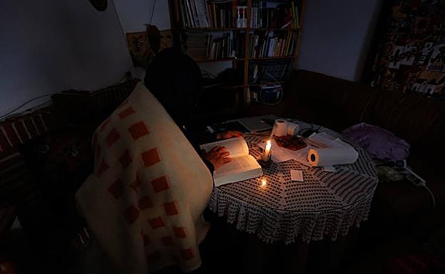 Uno de los afectados lee a oscuras en el salón de su casa. 