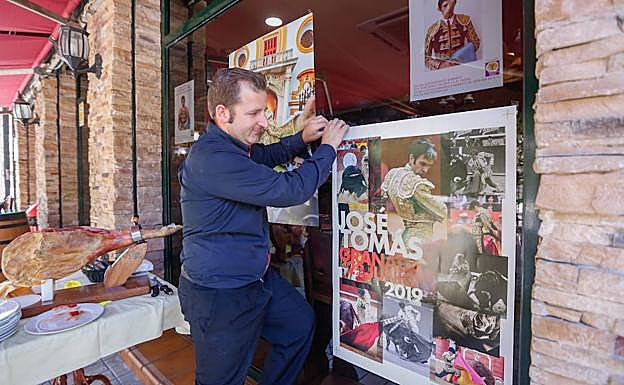 Colocando un cartel de José Tomás en un establecimiento hostelero.