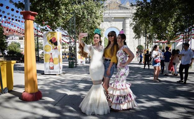 Tres chicas se hacen un 'selfie' en la portada del recinto ferial.