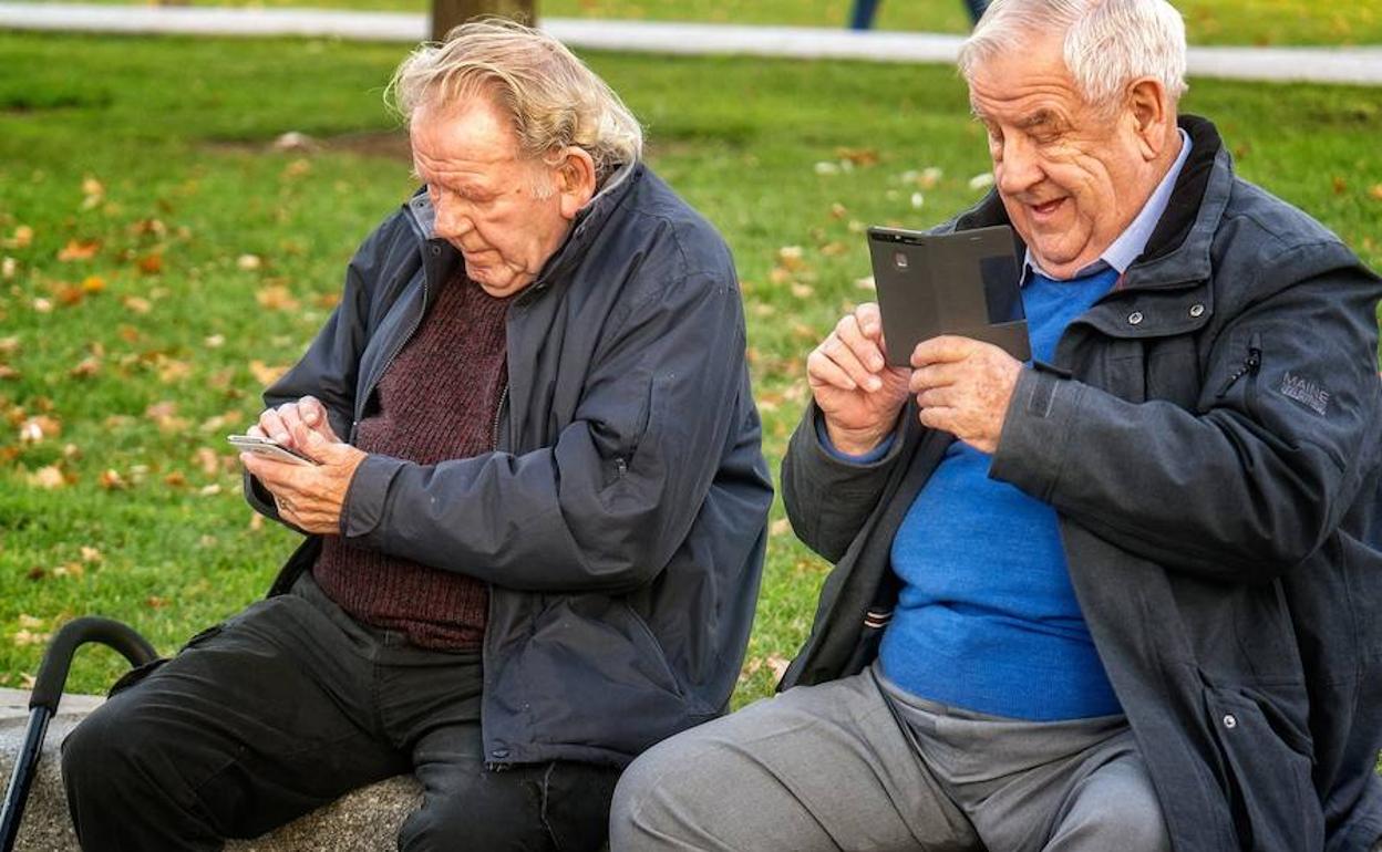 Dos hombres jubilados con su teléfono móvil.