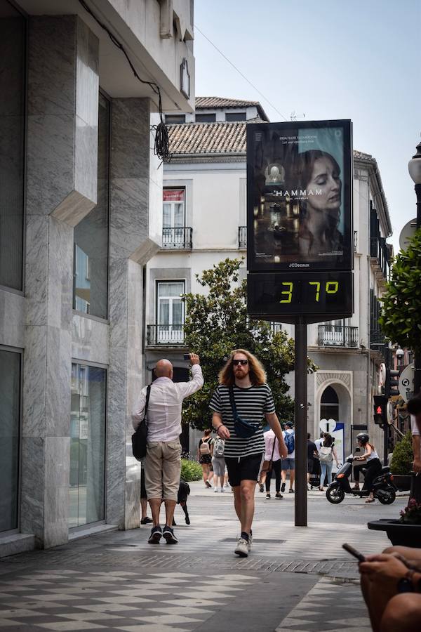 Granadinos y visitantes se las apañan en las calles para no sufrir mucho el enorme calor de estos días