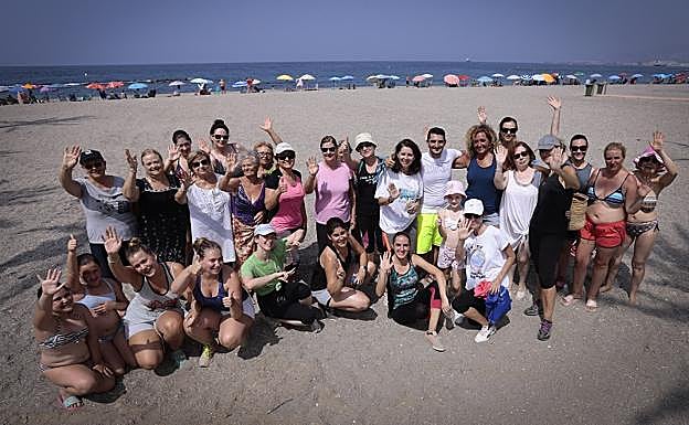 Un grupo de vecinos y veraneantes de Torrenueva Costa, que acaba de disfrutar de una clase de zumba sobre la arena, saluda a la cámara. 