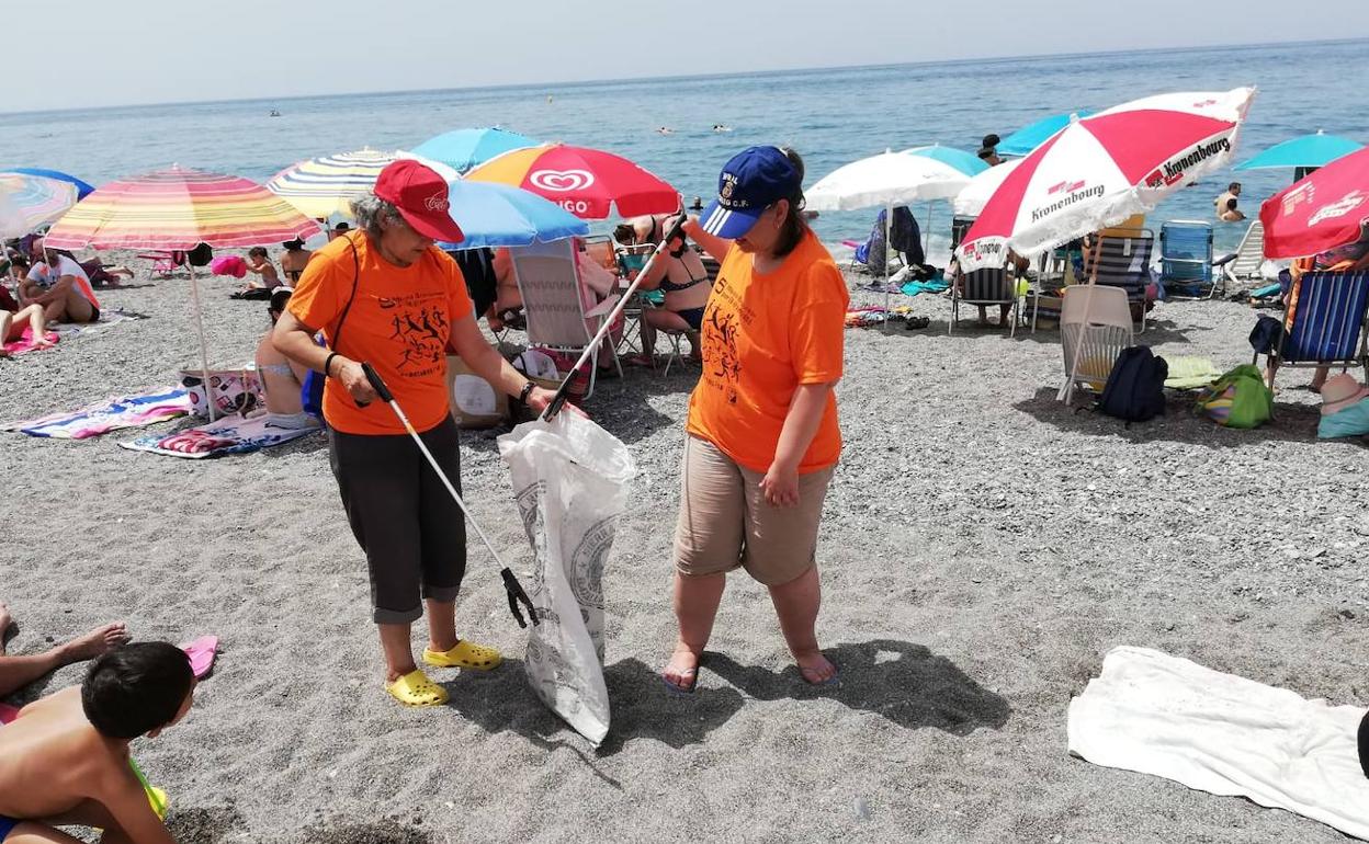 Dos de los participantes en el programa, limpiando la playa