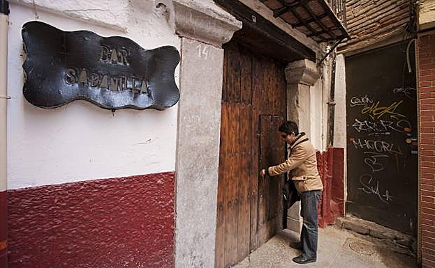 Imagen principal - 1. Paqui una de las inquilinas de la Taberna La Sabinilla abre la puerta del establecimiento (2010). 2 y 3: Comparativa de la calle y el edificio entre 2010 y 2019.